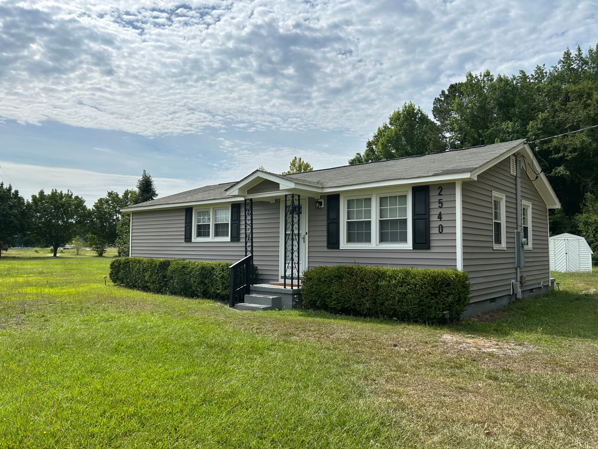 Front and side view of the remodeled ranch home with new siding and shutters